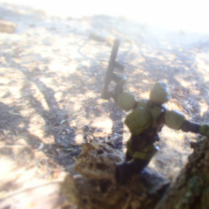 Space soldier leaning against tree on a branch looking below with gun raised upwards