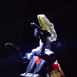 A robotic velociraptor looks upwards as a spotlight is on it.