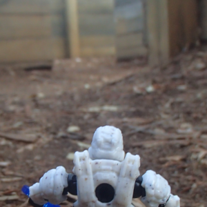 A white-armor space soldier in a wide wooden maze space with dirt floor, expectantly holding a blue energy sword.