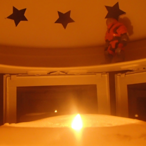 An orang-armored space soldier stands on the rim on the inside of a candle lantern with a lit candle.