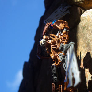 Low angle shot of a brown Bioncile holding robotic wings to climb up a cobblestone wall.